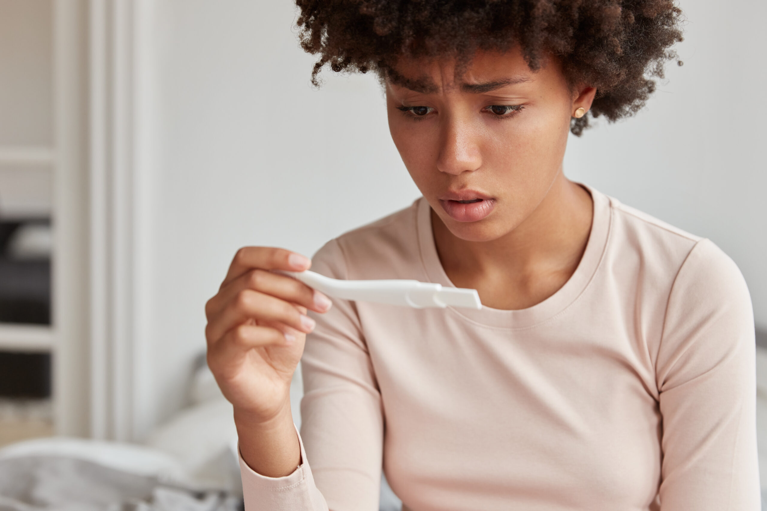 embrarrassed woman with afro hairstyle faces serious problem dissatisfied with pregnancy test scaled